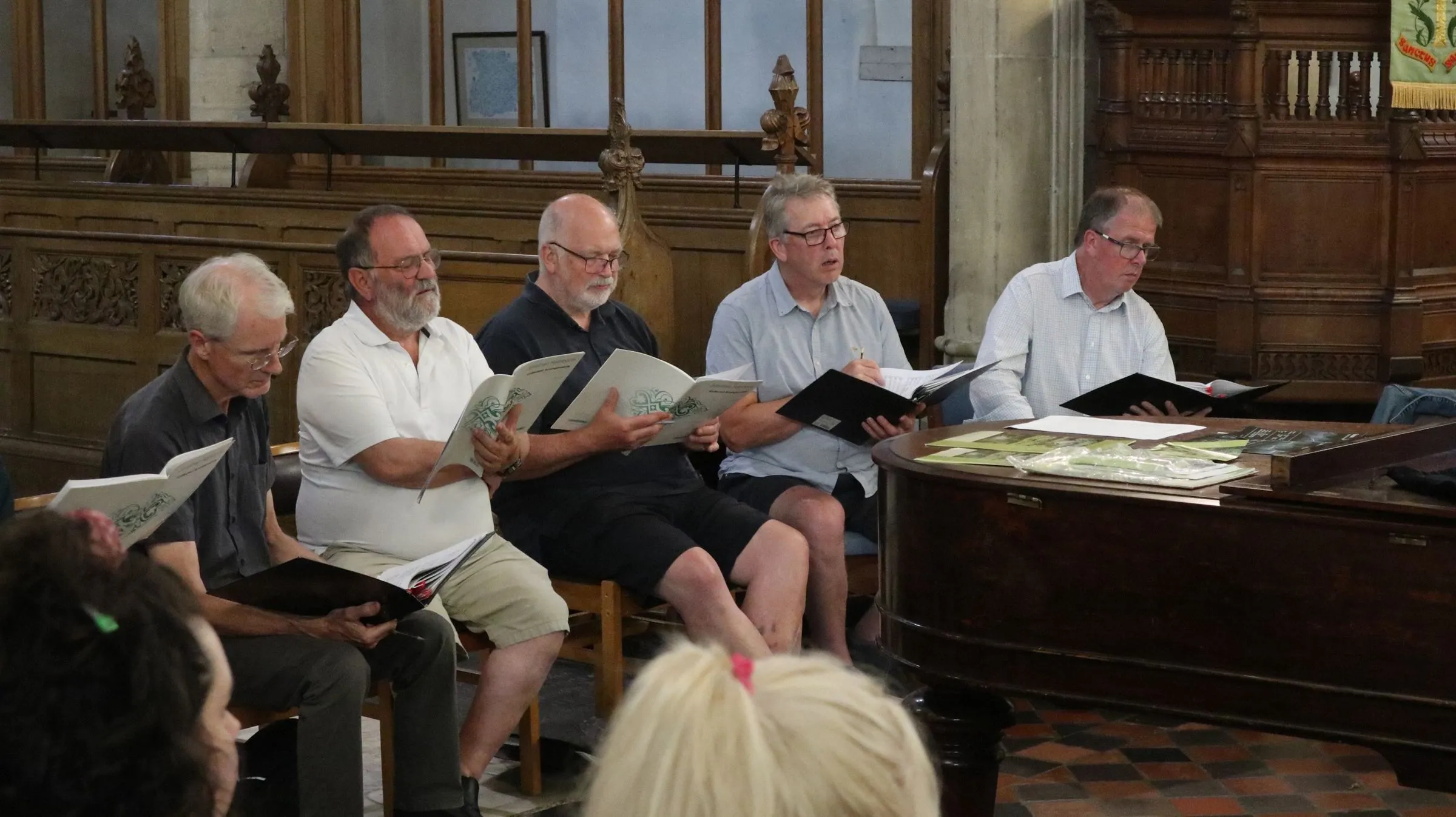 A row of basses seated by the piano, scores open
