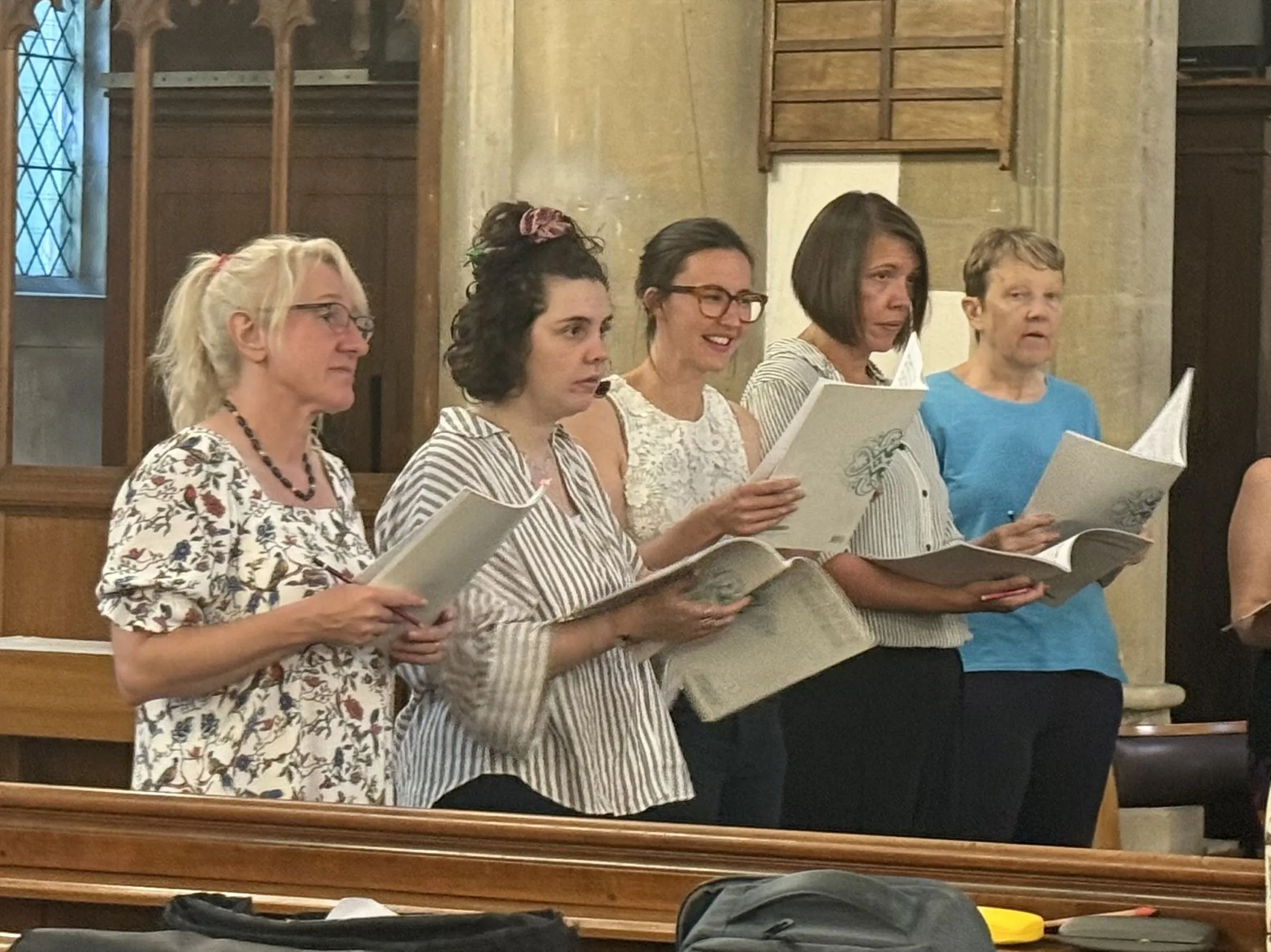 A row of sopranos standing and singing from their scores