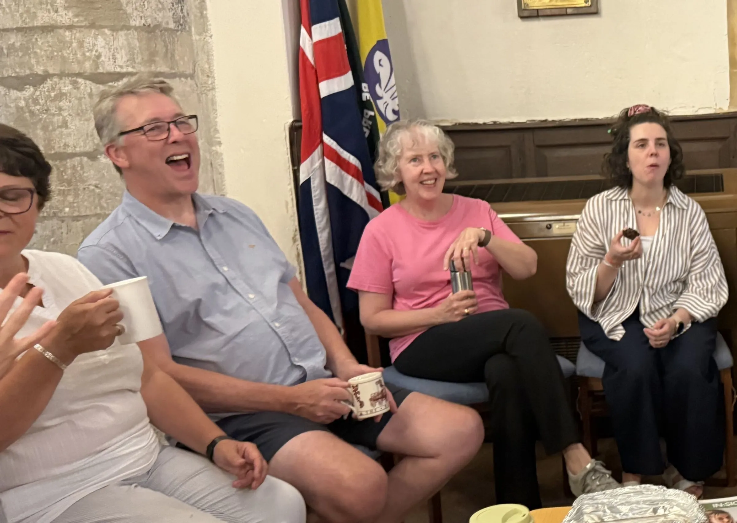 Choir members laughing over tea and cake in the rehearsal break