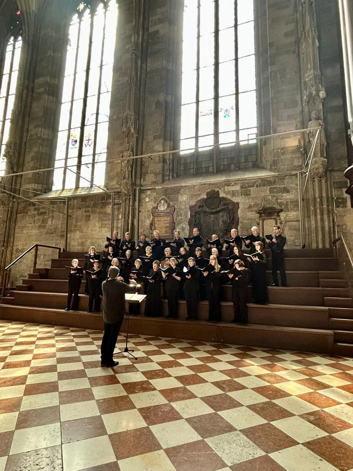 The choir seen from across a chequered floor, beneath tall Gothic windows